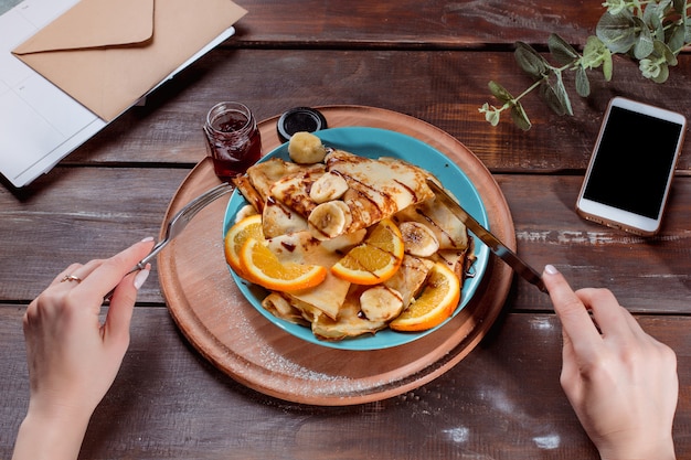 Las manos femeninas y panqueques con jugo. Desayuno saludable