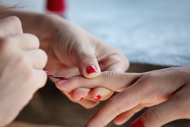 Foto gratuita manos femeninas pintadas las uñas con esmalte rojo