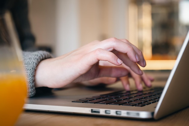 Las manos femeninas del primer están escribiendo en una computadora portátil