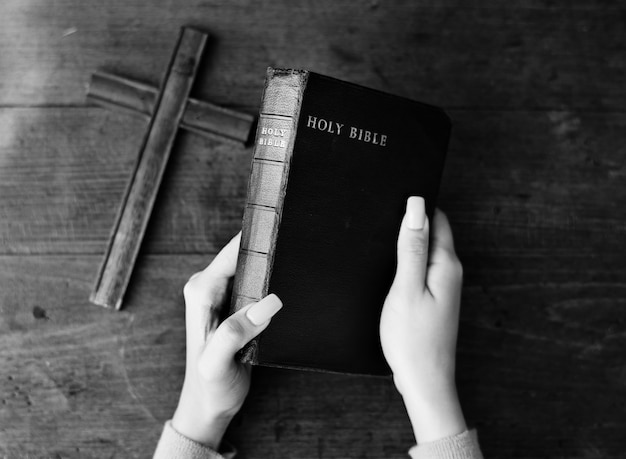 Foto gratuita manos femeninas sosteniendo una biblia y una cruz de madera