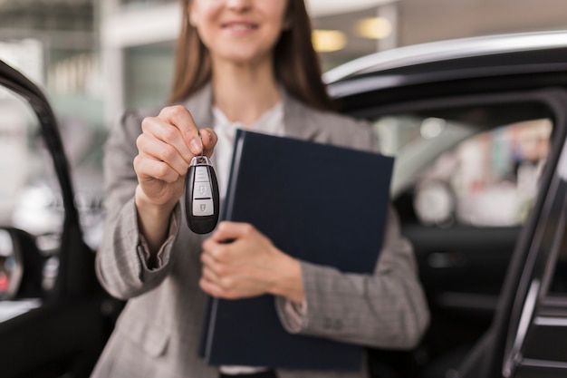 Manos femeninas sosteniendo una carpeta y las llaves del auto