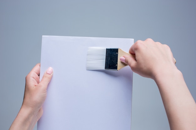 Manos femeninas sosteniendo pincel sobre lienzo blanco