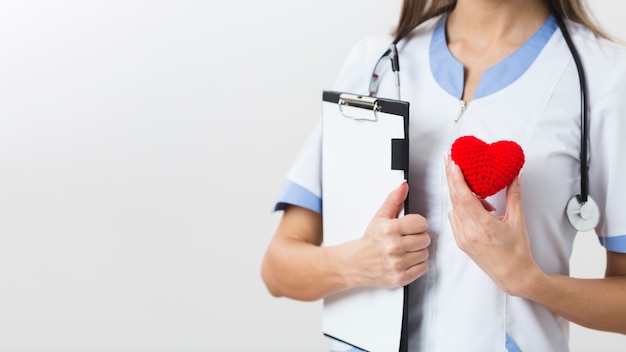 Foto gratuita manos femeninas sosteniendo un portapapeles y un corazón de felpa