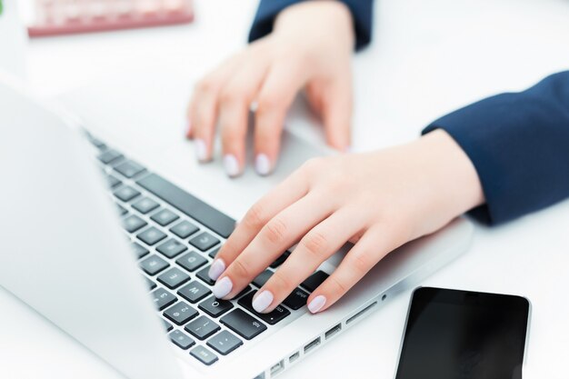 Las manos femeninas en el teclado de su computadora portátil