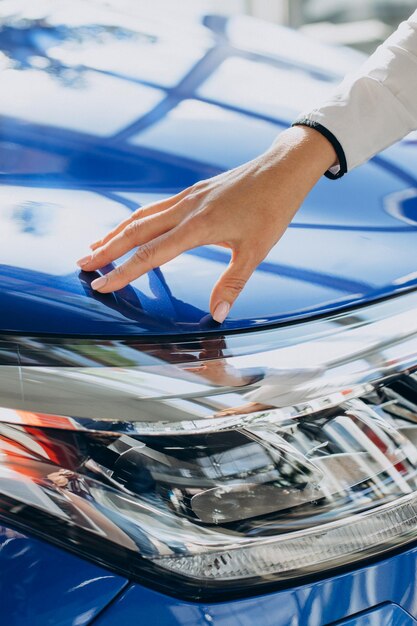 Manos femeninas tocando nuevo coche azul de cerca