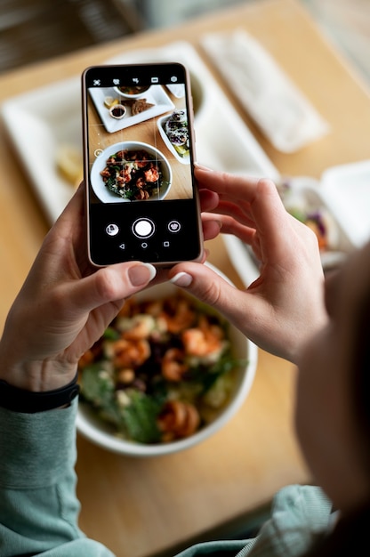 Manos femeninas tomando fotos de un bol con ensalada y una cazuela de repollo