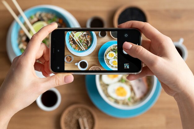 Manos femeninas tomando fotos de dos tazones de ramen