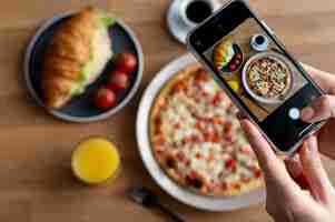 Foto gratuita manos femeninas tomando fotos de una pizza en rodajas y un croissant con queso