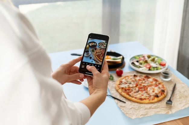 Manos femeninas tomando fotos de pizza en rodajas