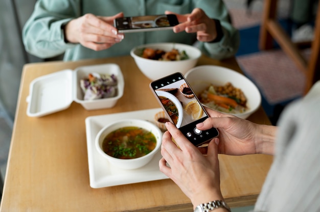 Manos femeninas tomando fotos de sopa y una rodaja de limón