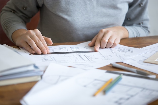 Manos femeninas, trabajando con una regla y un dibujo