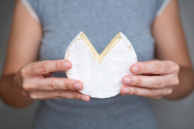 Manos femeninas con trozo de queso blando