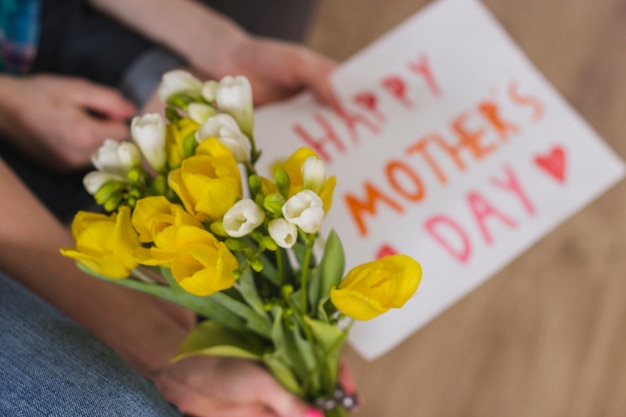 Manos con flores y cartel del día de la madre