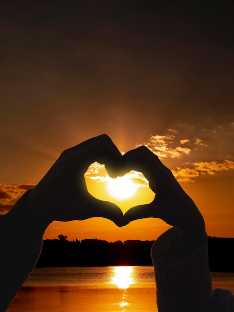 Foto gratuita manos en forma de corazón en una puesta de sol