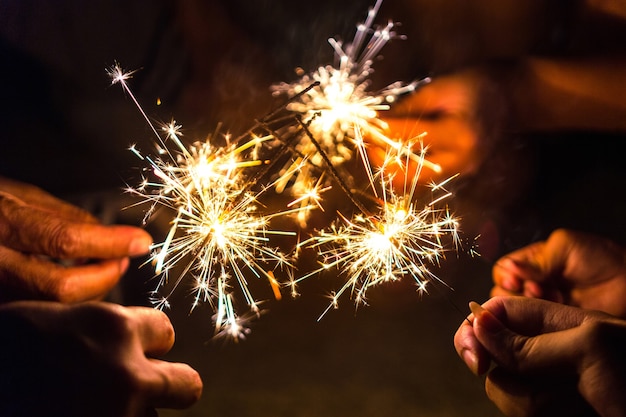 Manos de gente sosteniendo Bengala, Bengala festiva brillante de Navidad.