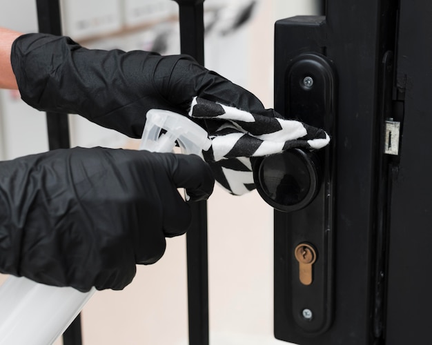 Foto gratuita manos con guantes desinfectando la manija de la puerta
