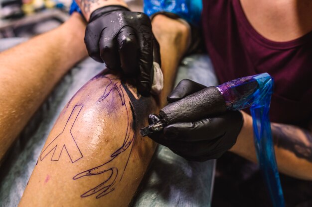 Manos en guantes dibujo tatuaje con máquina