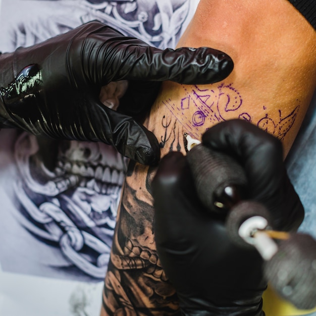 Manos en guantes haciendo tatuaje