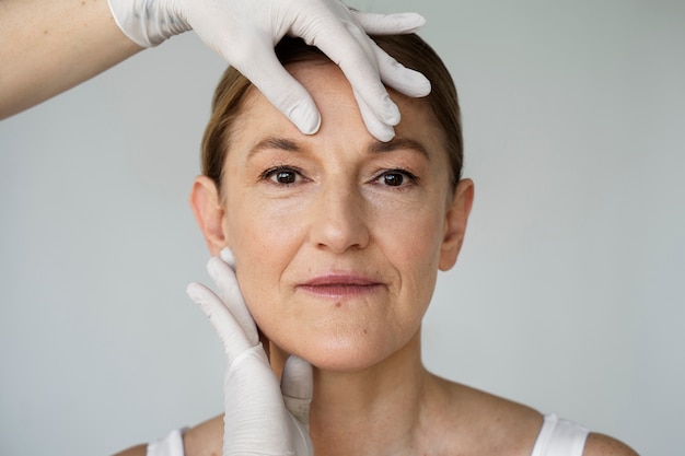 Foto gratuita manos con guantes sosteniendo la vista frontal de la cara de la mujer