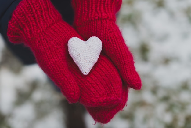 Manos con guantes sujetando un corazón blanco