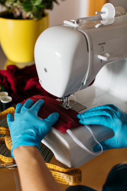 Foto gratuita manos con guantes terminando una mascarillas de tela