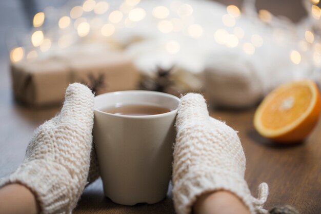 Manos con guantes tocando taza de té