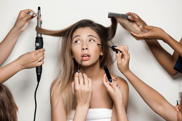 Manos haciendo maquillaje y peinado de joven bella mujer