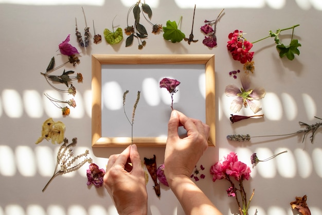 Foto gratuita manos haciendo un marco con flores prensadas