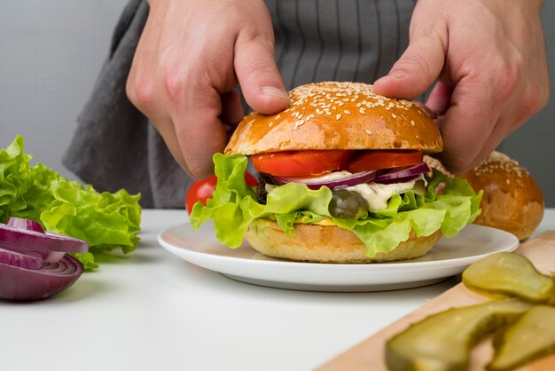 Manos haciendo una sabrosa hamburguesa