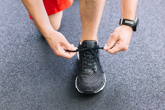 Manos del hombre atando zapatilla de deporte