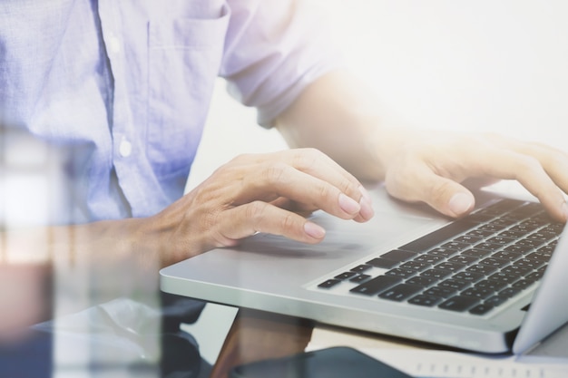 Las manos del hombre escribiendo en el teclado de la computadora portátil.