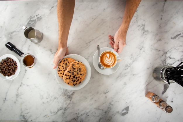 Foto gratuita manos de hombre con galletas y un capuchino