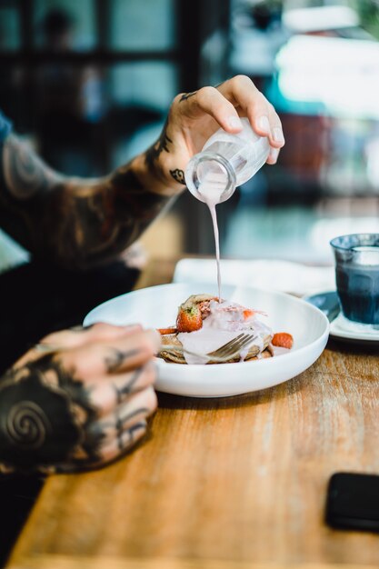 Las manos del hombre vierten salsa dulce en panqueques