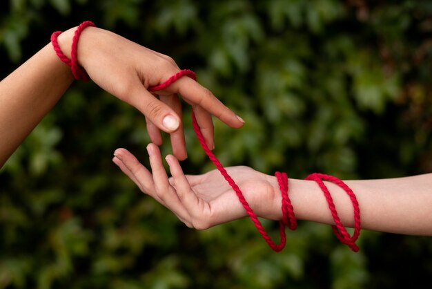 Manos humanas conectadas con hilo rojo