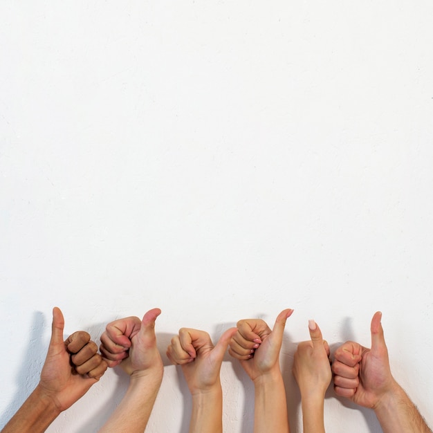 Foto gratuita manos humanas que muestran gesto de pulgar sobre pared con textura blanca