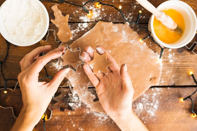 Manos humanas sosteniendo forma para galletas y masa