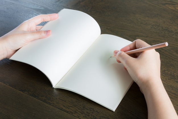 Manos con una libreta en blanco abierta y un lápiz