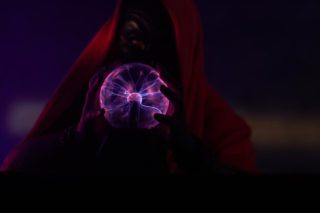 Las manos del mago oscuro controlan un globo mágico, mostrando efectos de iluminación.