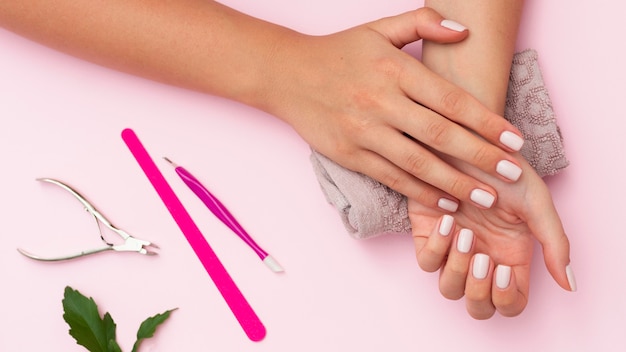 Manos con manicura y herramientas para el cuidado de las uñas