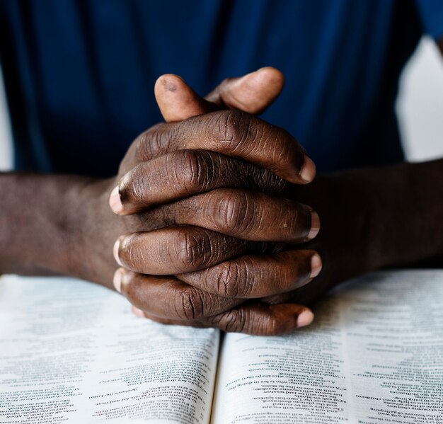 Manos masculinas afroamericanas descansando sobre una Biblia abierta