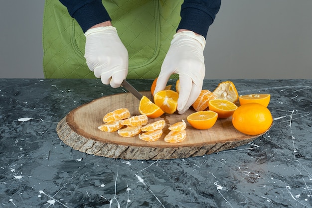 Manos masculinas cortando limón fresco en la mesa de mármol.