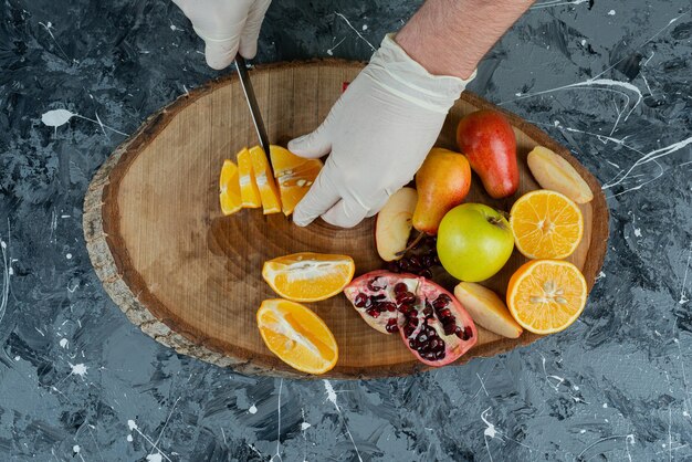 Manos masculinas cortando limón fresco en la mesa de mármol.