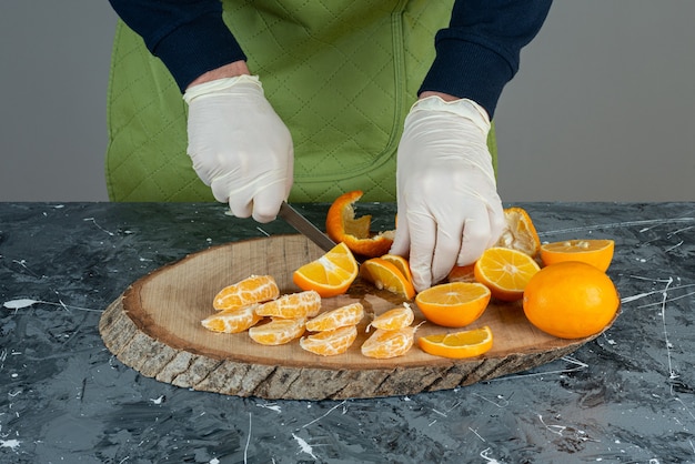 Manos masculinas cortando limón fresco en la mesa de mármol.