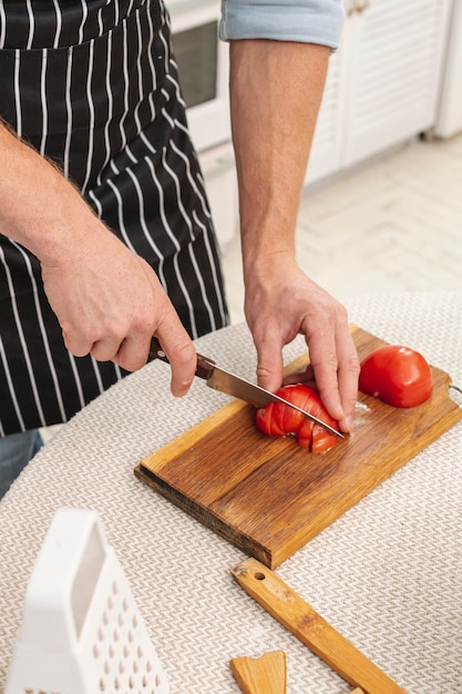 Manos masculinas cortando un tomate delicioso