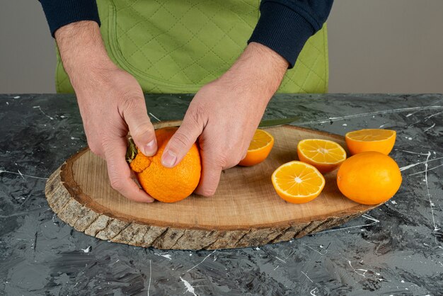 Manos masculinas sosteniendo jugosa mandarina en mesa de mármol.