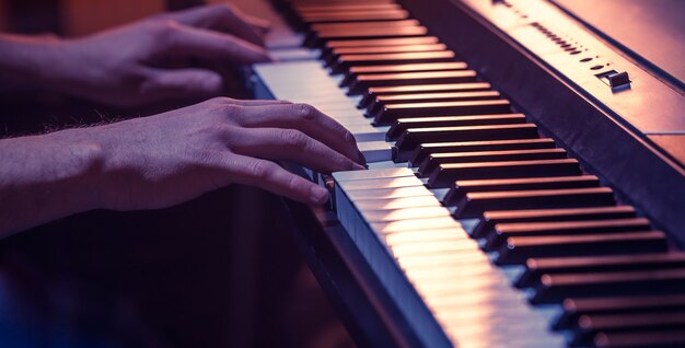 Manos masculinas en las teclas del piano primer plano de un hermoso fondo colorido, el concepto de actividad musical