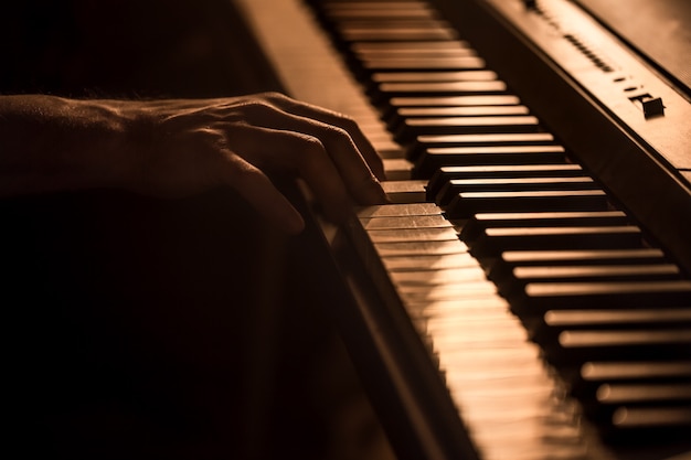 Manos masculinas en las teclas del piano primer plano de un hermoso fondo colorido, el concepto de actividad musical