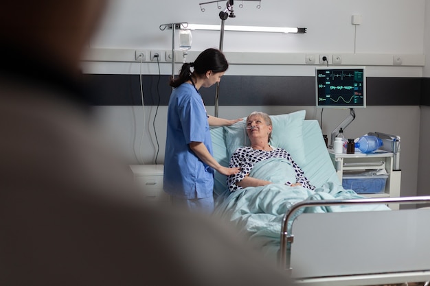 Foto gratuita manos del médico amigable sosteniendo la mano del paciente, en la habitación del hospital dando aliento, empatía, apoyo durante el examen médico