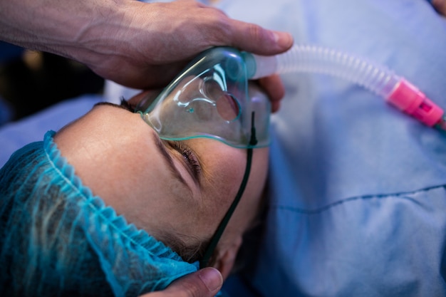 Manos del médico colocando una máscara de oxígeno en la cara de una mujer embarazada