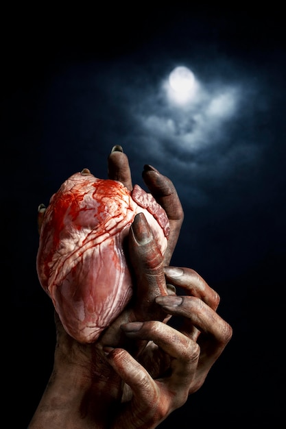 Manos de miedo mujer zombie sosteniendo un corazón